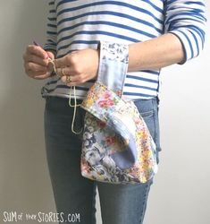 a woman in striped shirt holding a purse with flowers on it's front pocket