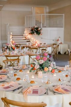 the tables are set for an event with white linens and floral centerpieces