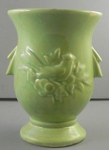 a green vase sitting on top of a table