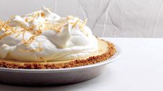 a pie with whipped cream and orange zest on top is sitting on a white table