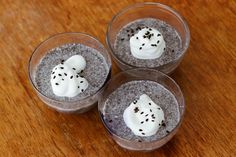 three desserts with white frosting and sprinkles in small glasses on a wooden table