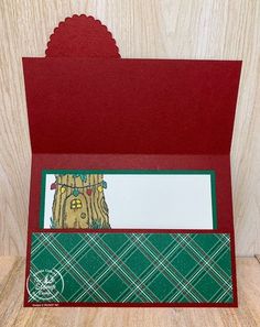 a close up of a card on a wooden surface with a tree and plaid pattern