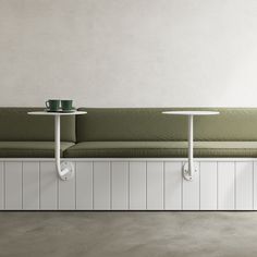 two tables sitting next to each other on top of a white bench with green cushions