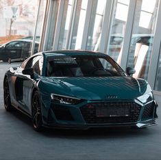 a blue sports car is parked in front of some large windows on the side of a building