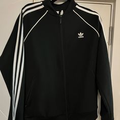 Never Worn, Just Not My Style. Black Track Jacket With Double-lined Hood, Black Long Sleeve Track Jacket With Double-lined Hood, Black Sportswear Outerwear With Double-lined Hood, Black Hooded Track Jacket For Fall, Adidas Long Sleeve Track Jacket With Three Stripes, Adidas Long Sleeve Track Jacket Athleisure, Adidas Long Sleeve Track Jacket In Athleisure Style, Adidas Long Sleeve Track Jacket For Athleisure, Adidas Long Sleeve Athleisure Track Jacket