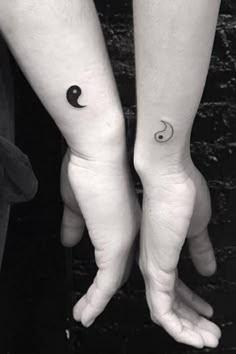 two people holding hands with tattoos on their arms and one has a crescent moon tattoo