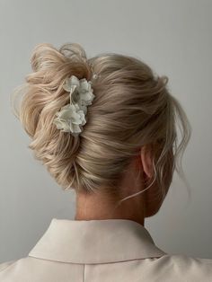 a woman with blonde hair and a flower in her hair is shown from the back