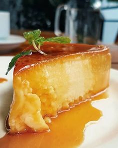 a piece of cheesecake on a plate with caramel sauce and mint sprig