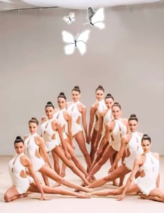 a group of women in white leotards posing for a photo with butterflies above them