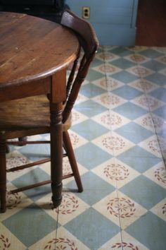 a wooden table and chair in a room with tile flooring on the ground, next to a blue door