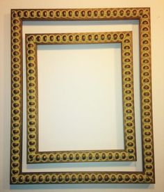 an ornate gold frame hanging on the wall above a white wall with circles in it