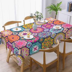 the table cloth is colorfully designed and has flowers on it, while two chairs sit in front