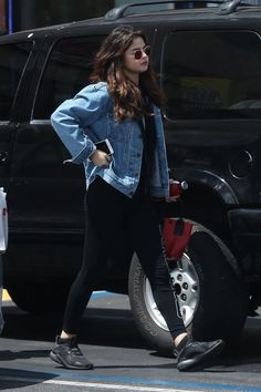 a woman in black leggings and a jean jacket crossing the street