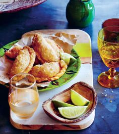 some food is sitting on a green plate and next to two glasses with wine in them