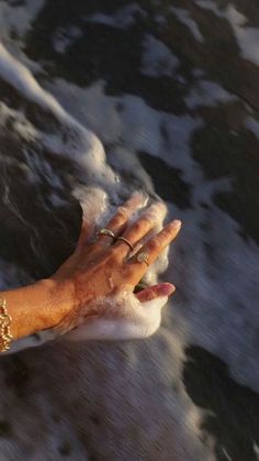 an old woman's hand holding something in the water with her left hand on it