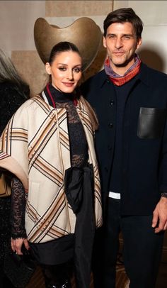 a man and woman standing next to each other in front of a heart shaped object