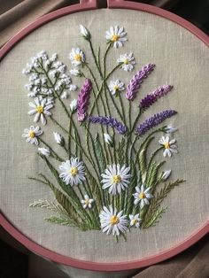 a close up of a embroidery on a piece of cloth with white and purple flowers