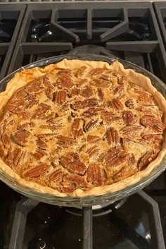 a pie sitting on top of a stove with pecans in the crusts and toppings