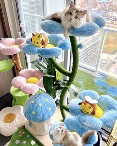 a cat sitting on top of a blue flower shaped plant next to other stuffed animals