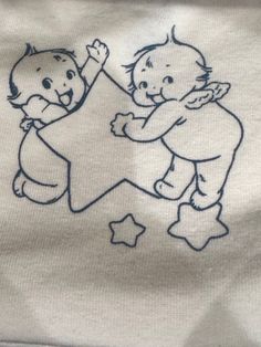 two babies playing with a star on a t - shirt that is embroidered onto it