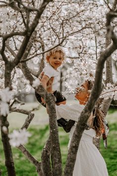 a woman holding a small child up in a tree