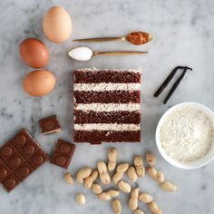 an assortment of food including chocolate, nuts and eggs on a marble counter top with utensils