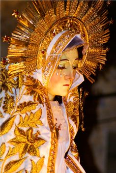 a woman dressed in gold and white is wearing an elaborate headdress