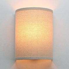 a wall light with a white fabric shade on the top and bottom part of it