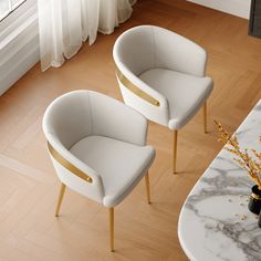 two white chairs sitting next to each other on top of a hard wood floored floor