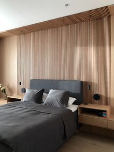 a large bed sitting in a bedroom next to a wall with wooden slats on it