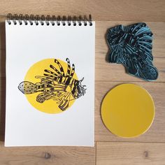 a spiral notebook with an image of a bee on it next to a yellow circle