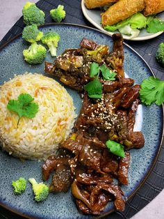 a blue plate topped with meat and rice next to broccoli on a table