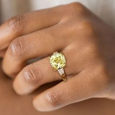 a woman's hand wearing a yellow diamond ring