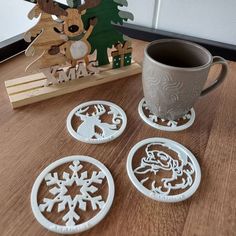 four coasters sitting on top of a wooden table next to a cup and mug