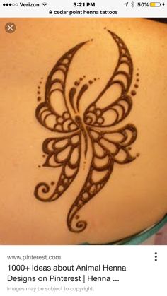 the back of a woman's shoulder with henna tattoos on it and an intricate butterfly