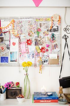 a white desk topped with lots of clutter and flowers next to a pink heart