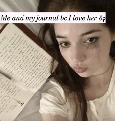 a woman laying on top of a bed next to an open book with writing on it