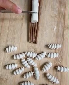 a person cutting up some food on top of a wooden table next to chopping utensils