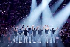 a group of men standing on top of a stage with their hands in the air