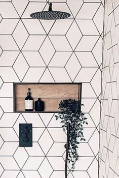 a white tiled bathroom with black and white tiles on the walls, a potted plant in the corner