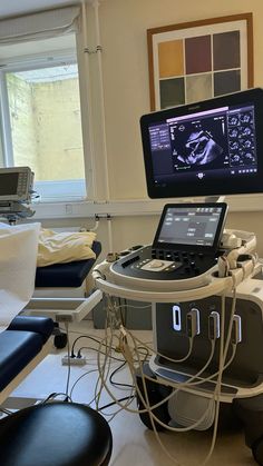 a laptop computer sitting on top of a hospital bed next to a monitor and chair