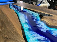 a wooden table with blue and white paint on it, next to a surfboard