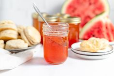 there is a jar of jam next to some watermelon and other food items