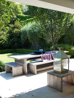 a wooden bench sitting on top of a patio next to a tree filled yard with lots of greenery