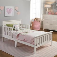 a child's bedroom with white furniture and pink accents