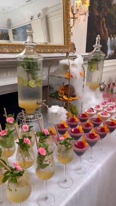 a table topped with lots of glasses filled with liquid and food on top of it