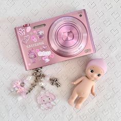 a pink camera sitting on top of a table next to charms and a keychain