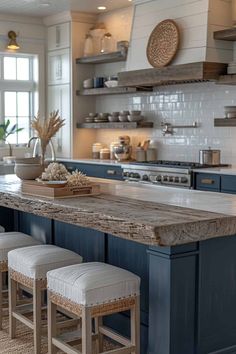 a large kitchen with blue cabinets and counter tops, along with two stools that are facing the center island