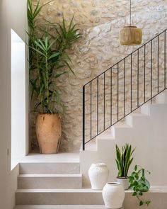 two white vases sitting on the steps in front of a stone wall and planter