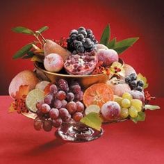 a bowl filled with lots of fruit on top of a red tablecloth covered table